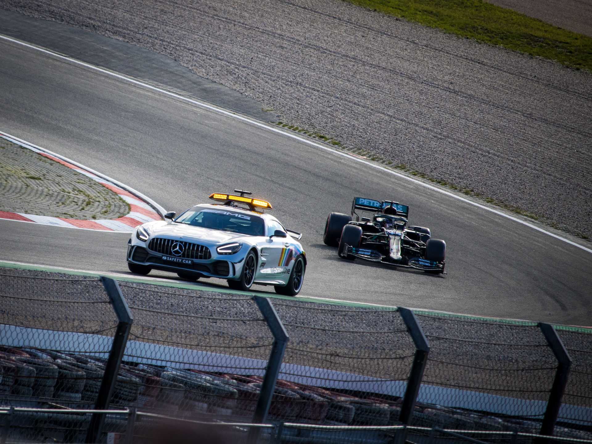 Mercedes Safety Car driving through a corner in front of a black mercedes formula 1 car